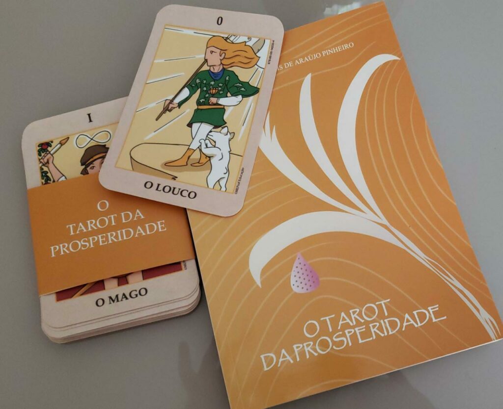 Imagem de cartas de tarot ao lado do livro "O tarot da prosperidade"