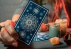 Imagem de uma taróloga segurando uma carta de tarot na mão como se estivesse mostrando para alguém