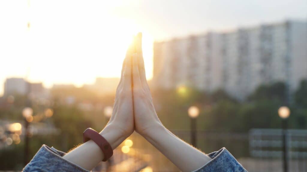 Imagem de uma pessoa com as mãos unidas em oração como se estivesse sentindo gratidão