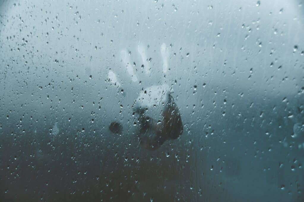 Marca de mão em uma janela molhada pela chuva.