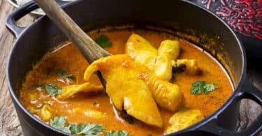 Peixe cozido dentro de uma panela com molho curry