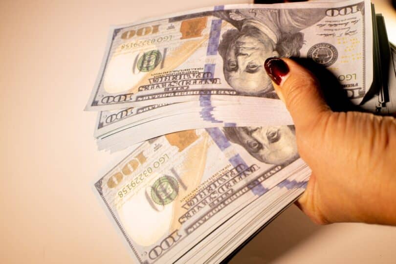 Mulher contando várias notas de dinheiro falso nas mãos