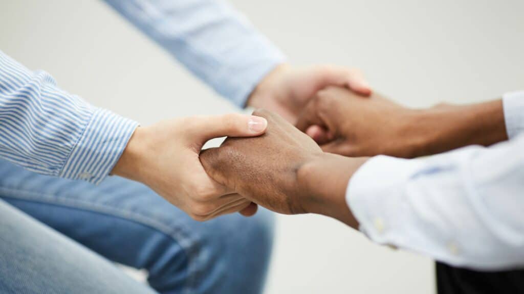 Imagem só das mãos dadas de duas pessoas, como se uma tivesse apoiando a outra.