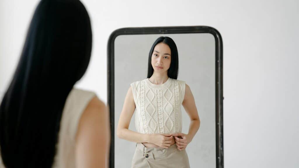 Imagem de uma mulher se olhando no espelho de corpo inteiro