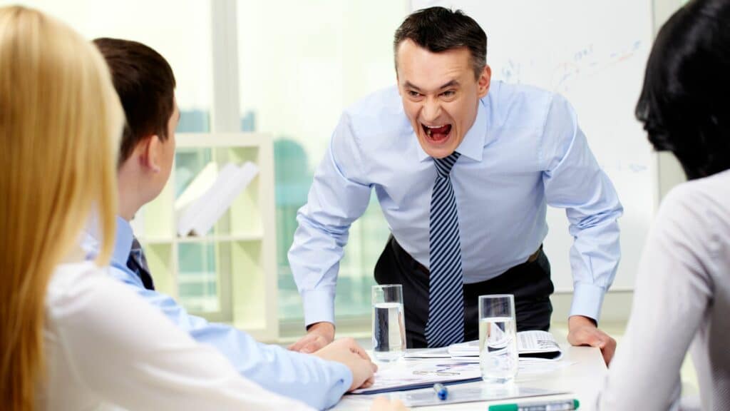 Imagem de um chefe gritando com seus funcionários em uma reunião