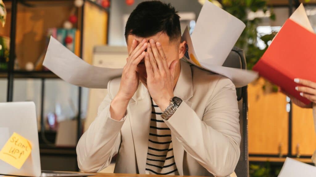 Imagem de um homem com as mãos no rosto em seu escritório como se estivesse sobrecarregado