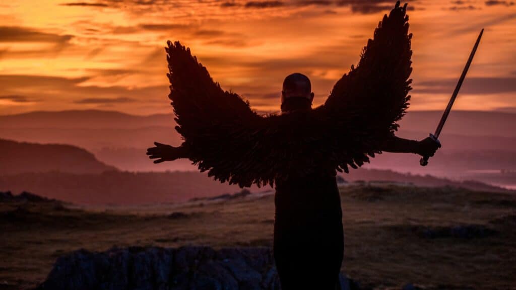 Imagem de um anjo com uma espada na mão e ao fundo o céu alaranjado por causa do sol