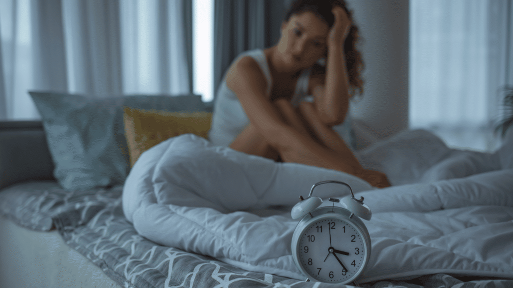 Mulher acordada na cama olhando para o despertador