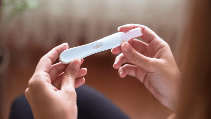 Pessoa segurando teste de gravidez positivo