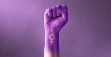 Mão de uma mulher levantada em pró do movimento feminista.