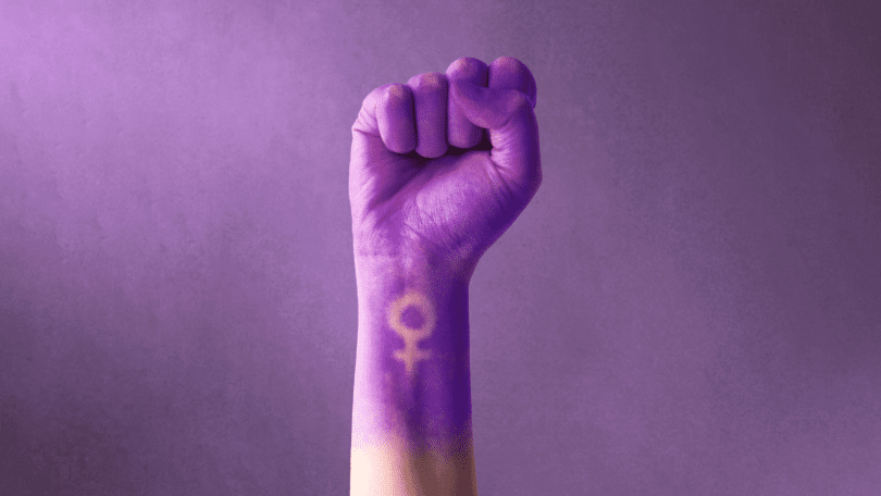 Mão de uma mulher levantada em pró do movimento feminista.
