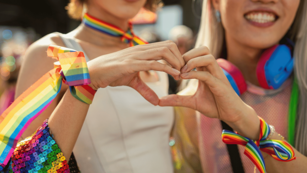 Duas amigas fazendo o símbolo de coração na parada LGBTQIA+ 