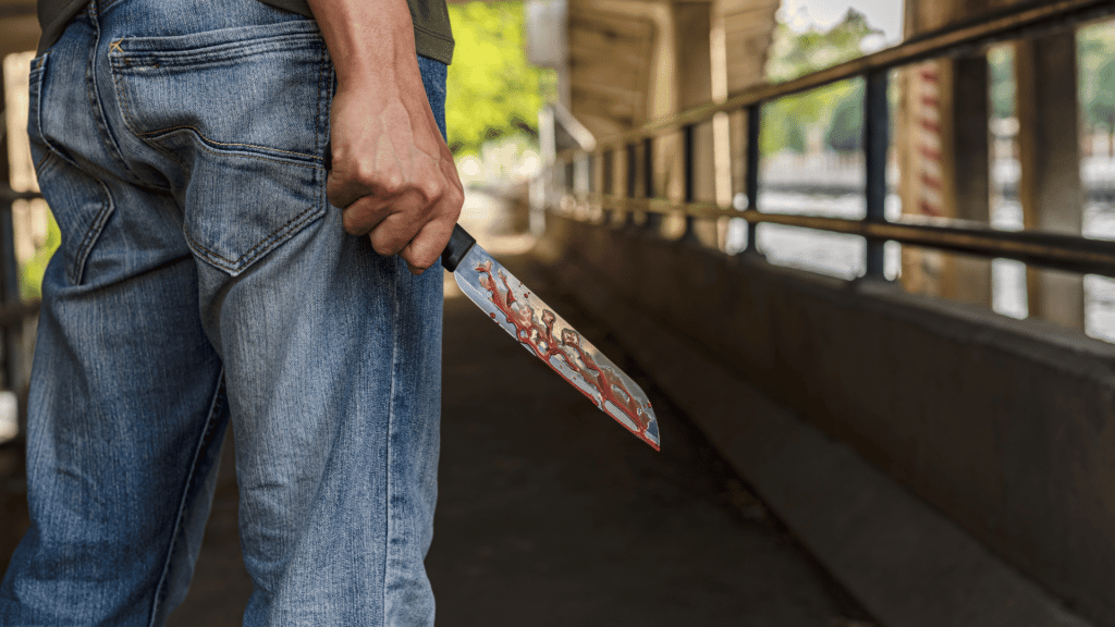 Homem segurando uma faca com sangue. 
