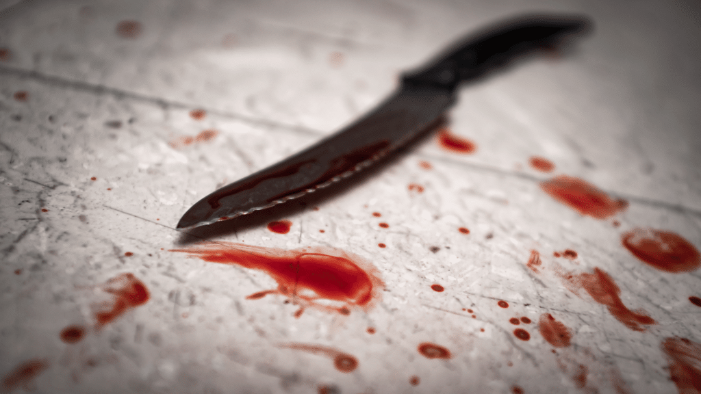 Faca pequena no chão com respingos de sangue ao seu redor.