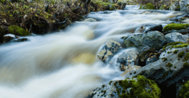 Imagem de uma corrente de rio em meio de pedras.