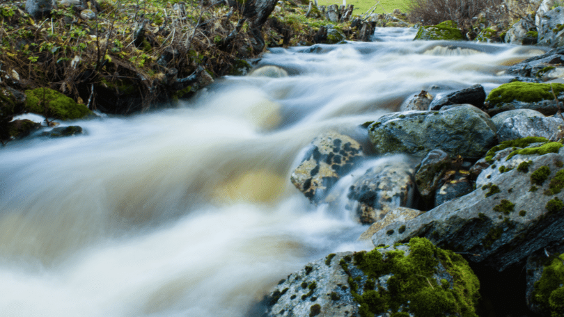 Imagem de uma corrente de rio em meio de pedras.