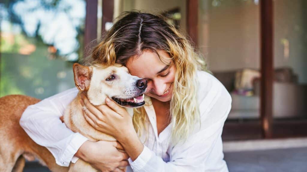 Imagem de uma mulher abraçando seu cachorro