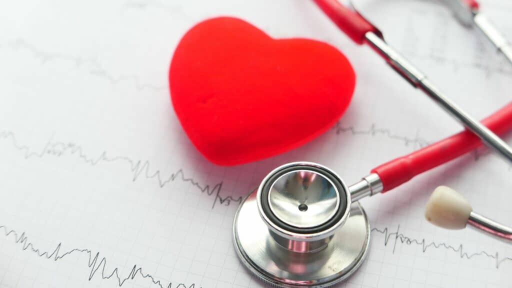 Imagem de um estetoscópio, um coração e o gráfico do exame para batimentos cardíacos