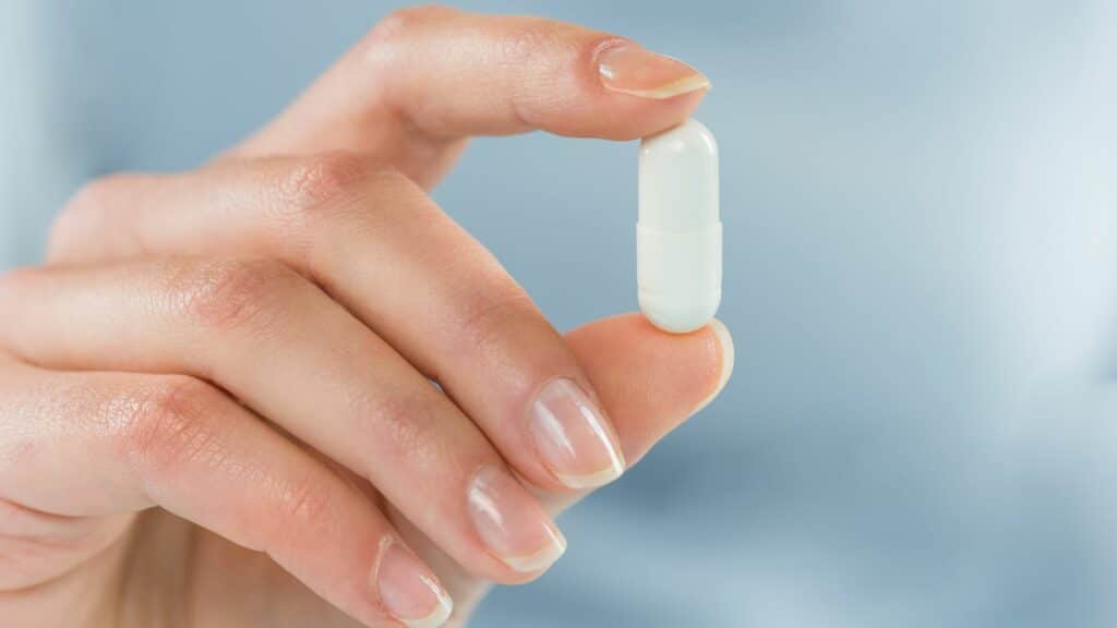 Imagem de mãos femininas segurando uma cápsula de remédio