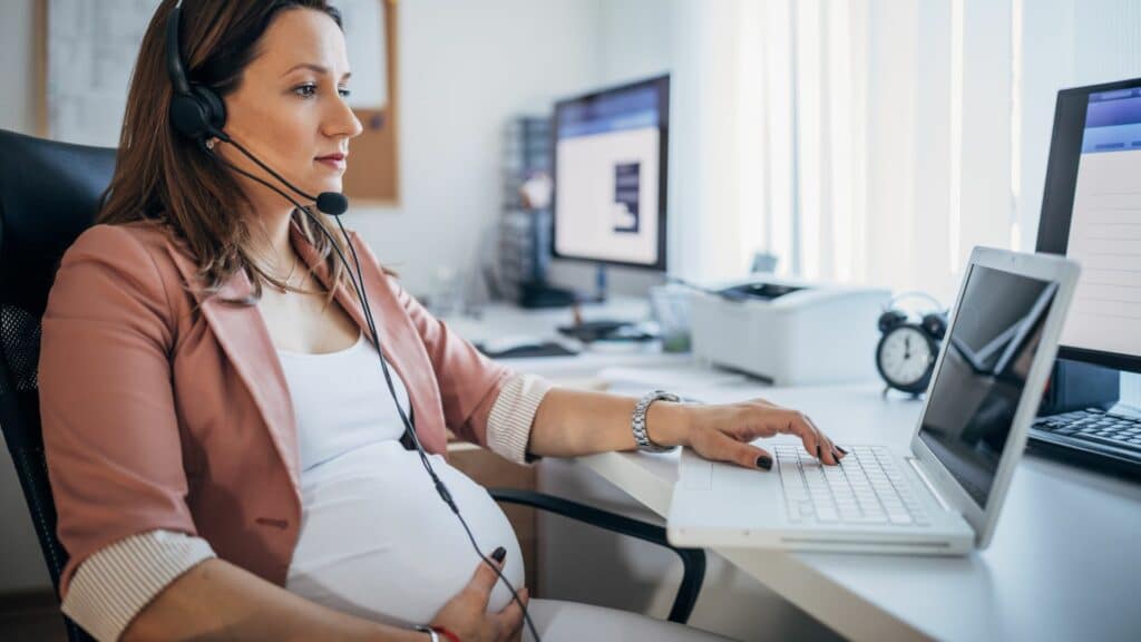 Imagem de uma grávida trabalhando em um escritório na frente de seu laptop