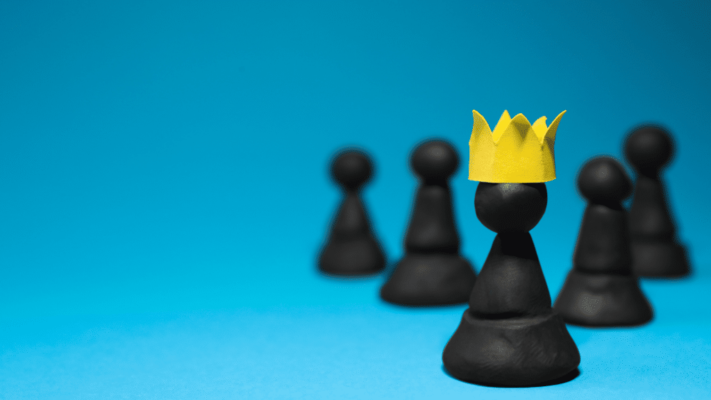 Peças de xadrez representando o ego, enquanto apenas uma usa uma coroa de papel