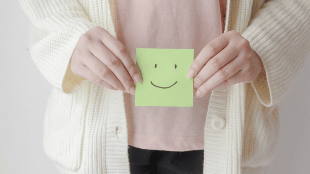 Pessoa segurando papel com uma carinha feliz desenhada