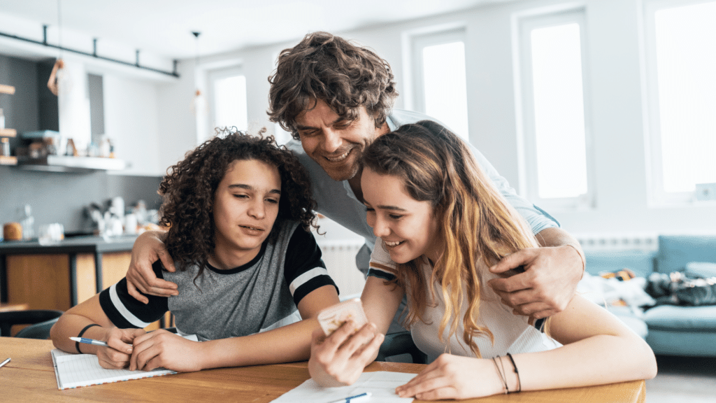 Pai e filhas adolescentes vendo alguma coisa engraçada no celular. 