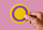 Mãos segurando um círculo amarelo com roxo simbolizando bandeira Intersexo.
