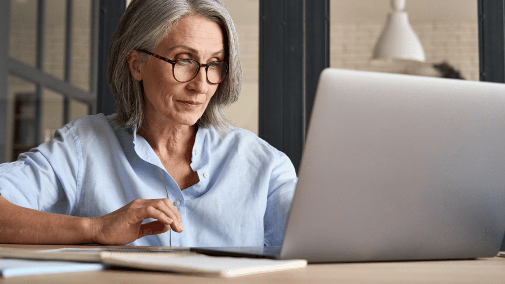 Mulher mais velha trabalhando em seu computador. 
