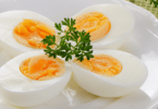 Imagem de quatros ovos cozidos em um prato com arranjo verde.