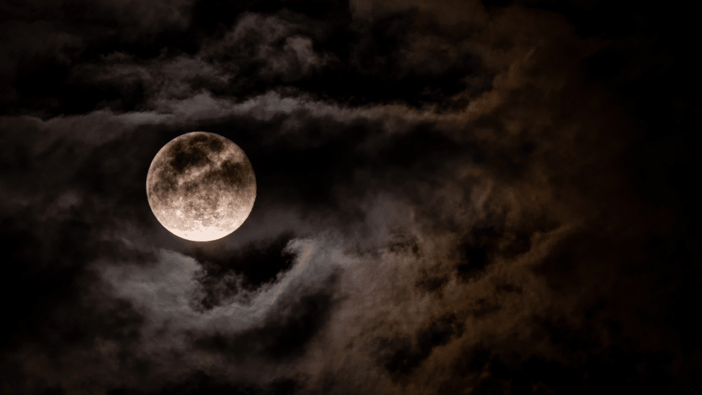 Foto de lua cheia em céu cheio de nuvens. 