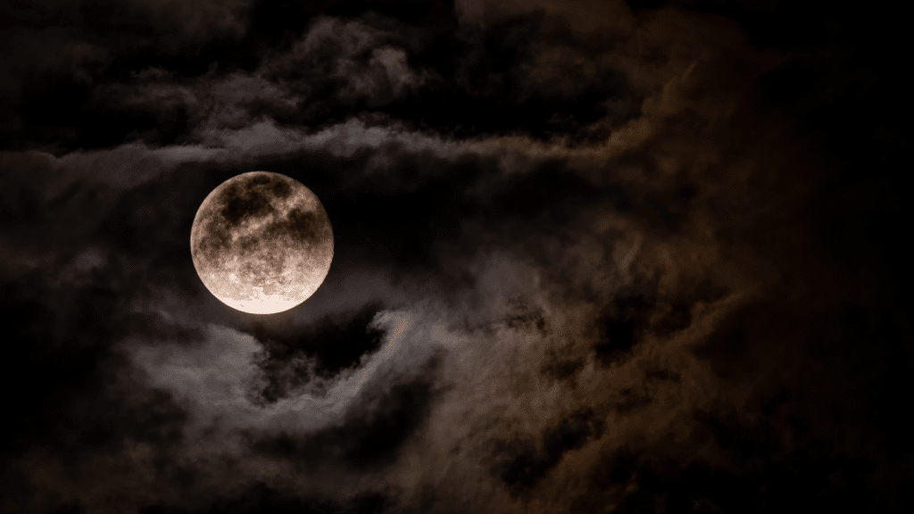 Foto de lua cheia em céu cheio de nuvens.