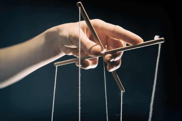 Mão manipulando cordas de marionete