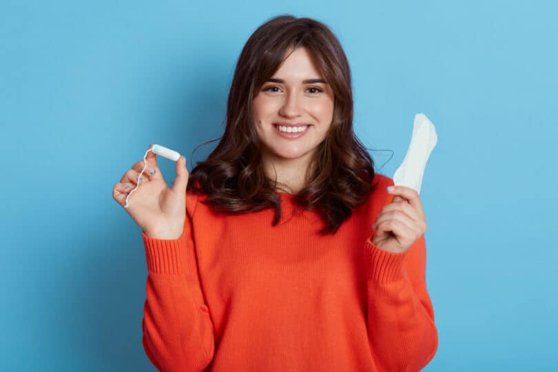 Mulher sorrindo segurando um absorvente e um o.b