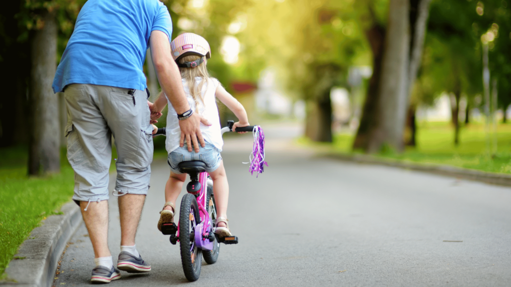 Criança aprendendo a andar de bicicleta. 