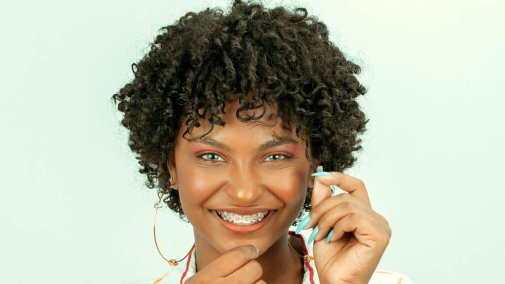 Imagem de uma  mulher negra sorrindo com o cabelo cacheado e curto