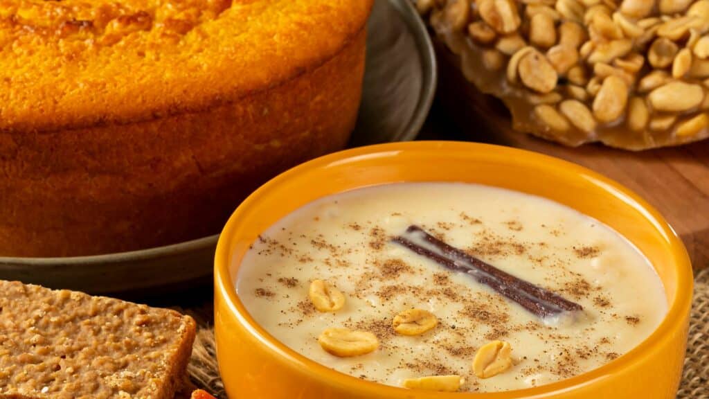 Imagem de bolo de fubá, arroz doce e paçoca em cima de uma mesa