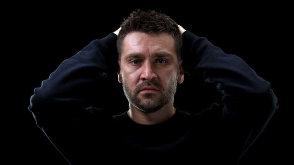 Imagem de um homem com semblante de arrependimento com as mãos na cabeça