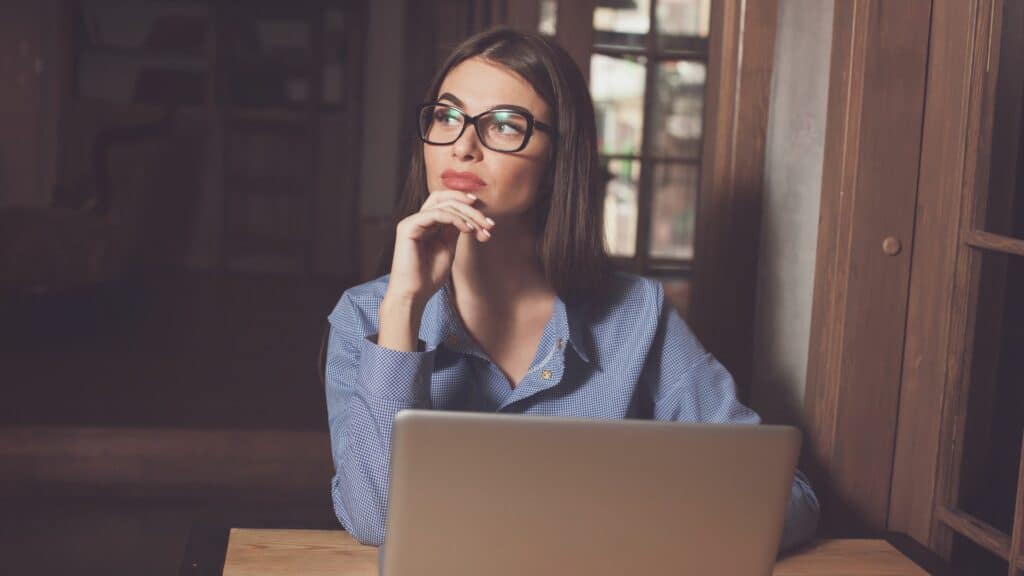 Imagem de uma mulher pensando na frente de um computador