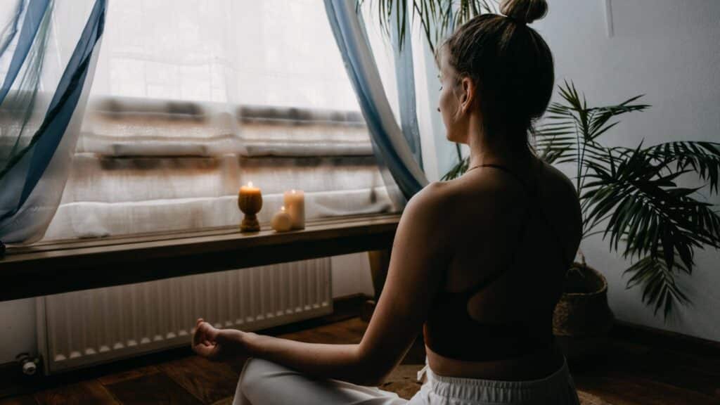Mulher meditando na frente de uma janela 