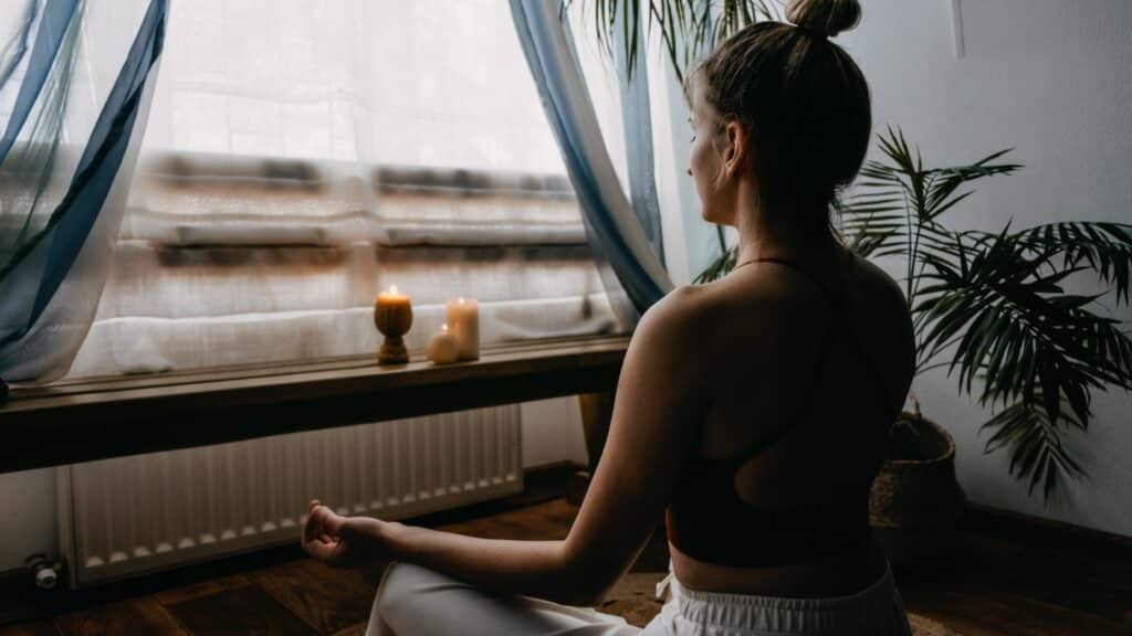 Mulher meditando na frente de uma janela