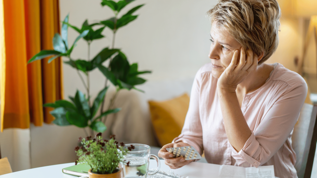 Mulher com feição de preocupada com sua menopausa.