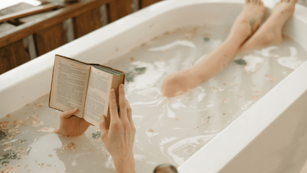 Mulher tomando banho numa banheira enquanto lê um livro