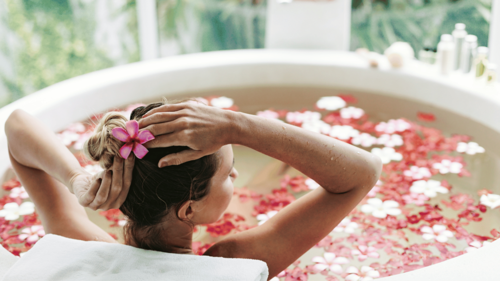 Mulher em uma banheira, tomando um banho relaxante com flores. 