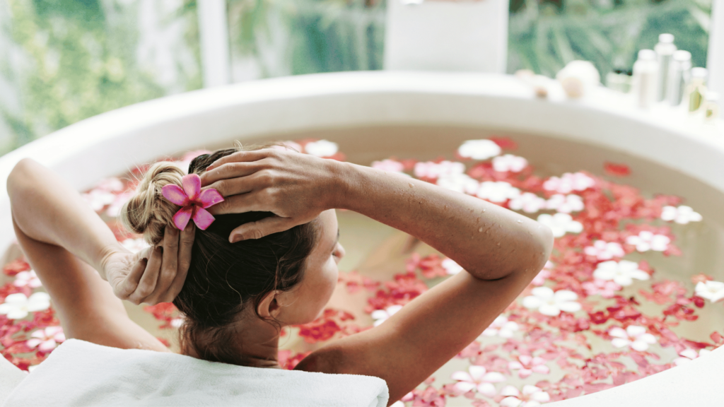 Mulher em uma banheira, tomando um banho relaxante com flores.