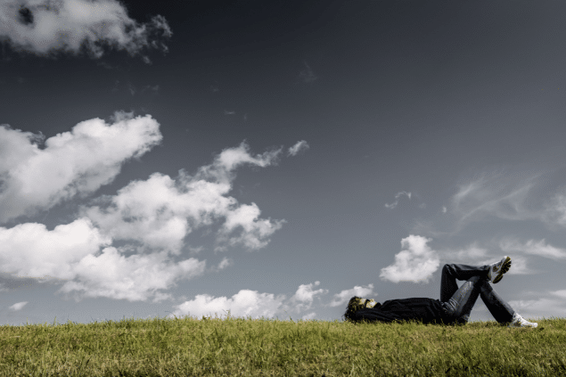 Homem deitado na grama e olhando para o céu