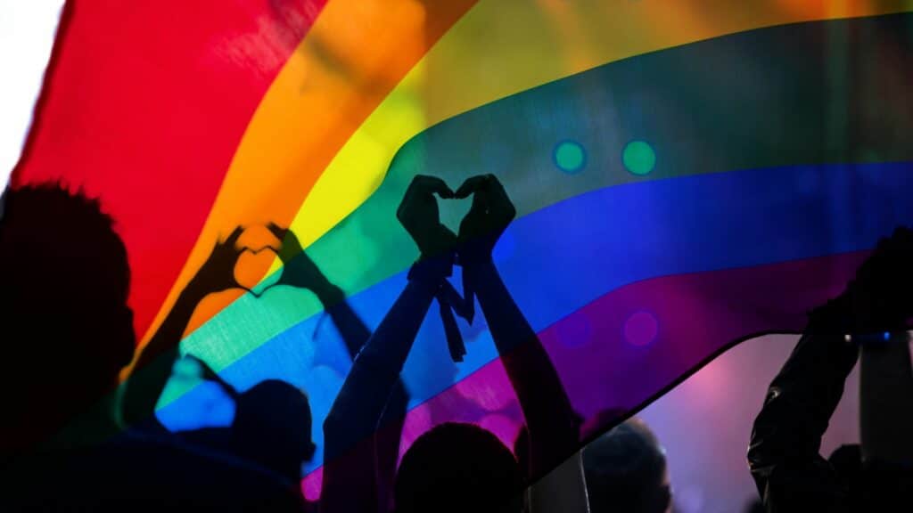 silhueta de pessoas em uma parada LGBTQIA+ fazendo corações com as mãos