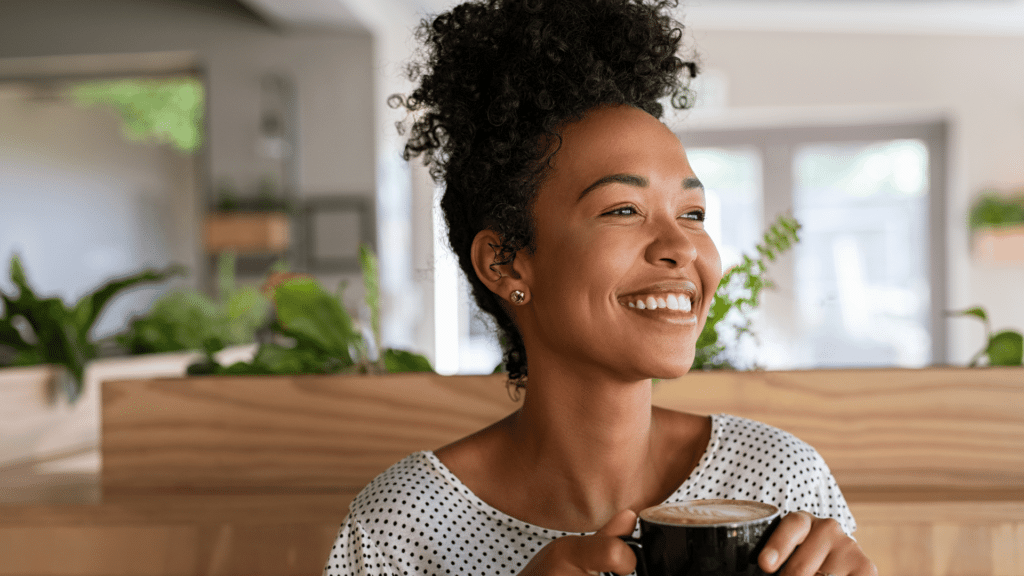 Mulher negra tomando café enquanto se sente otimista e feliz. Conceito de otimismo e positividade.