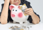 Mulher velhinha asiática sem dinheiro no cofre de porquinho.