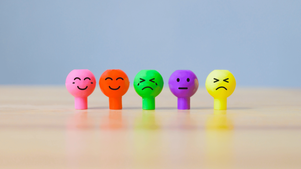 Bonequinhos coloridos representando as emoções feliz, triste, irritado e com tédio.